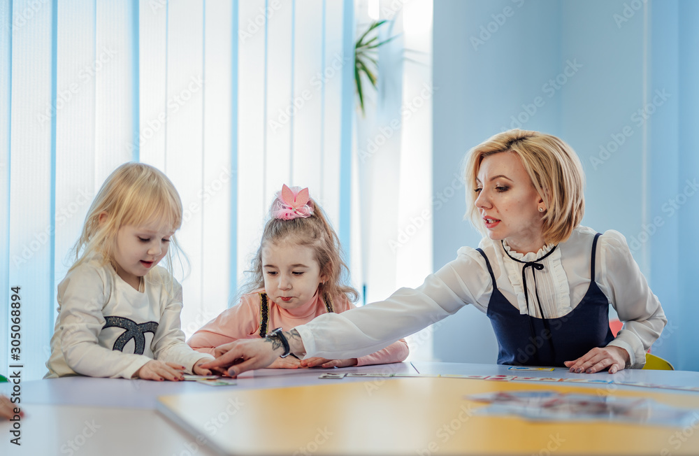 Two girls of elementary age in class with teacher. New methods of studing. Preschool concept.