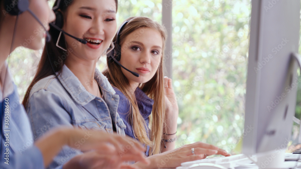 Customer support agent or call center with headset works on desktop computer while supporting the cu