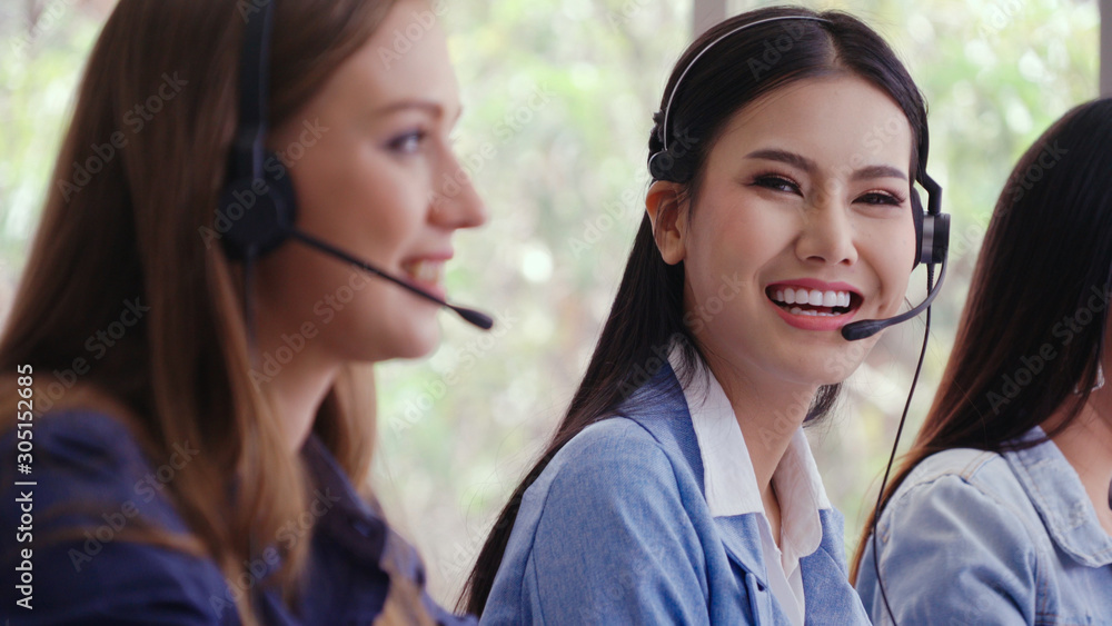 Customer support agent or call center with headset works on desktop computer while supporting the cu