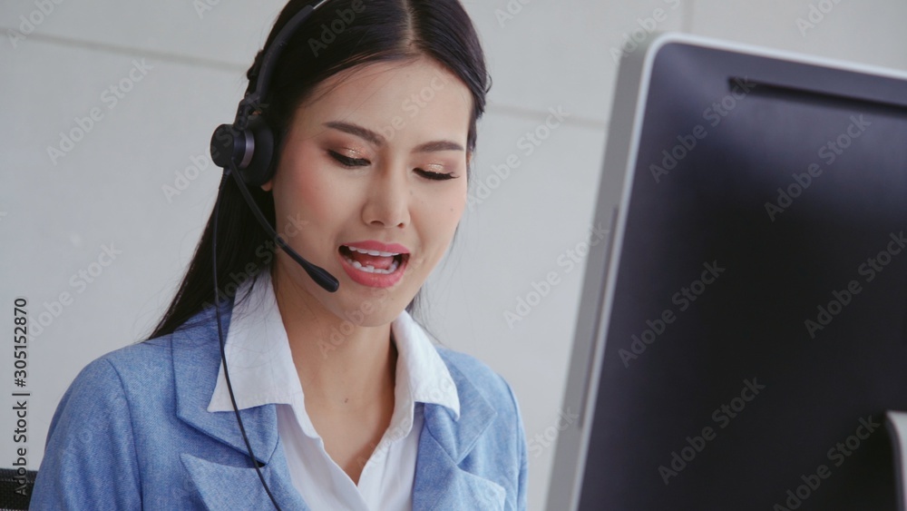 Customer support agent or call center with headset works on desktop computer while supporting the cu