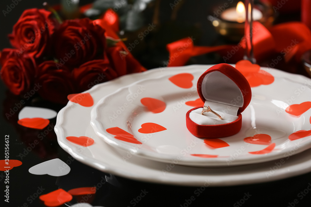 Box with beautiful ring and hearts on plate. Valentines Day celebration