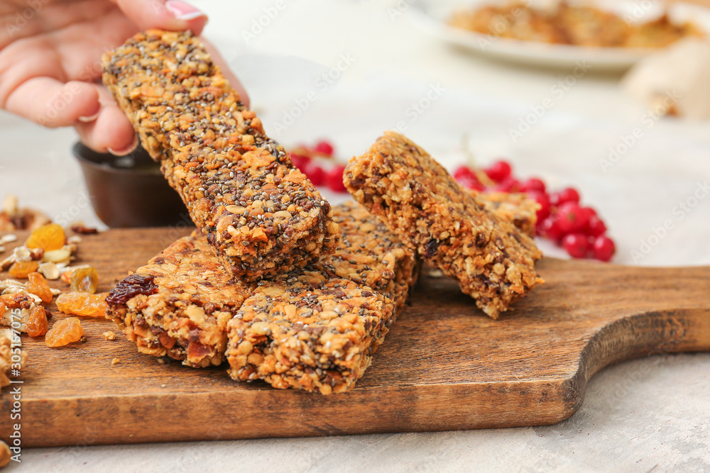 Woman taking tasty granola bar from table, closeup