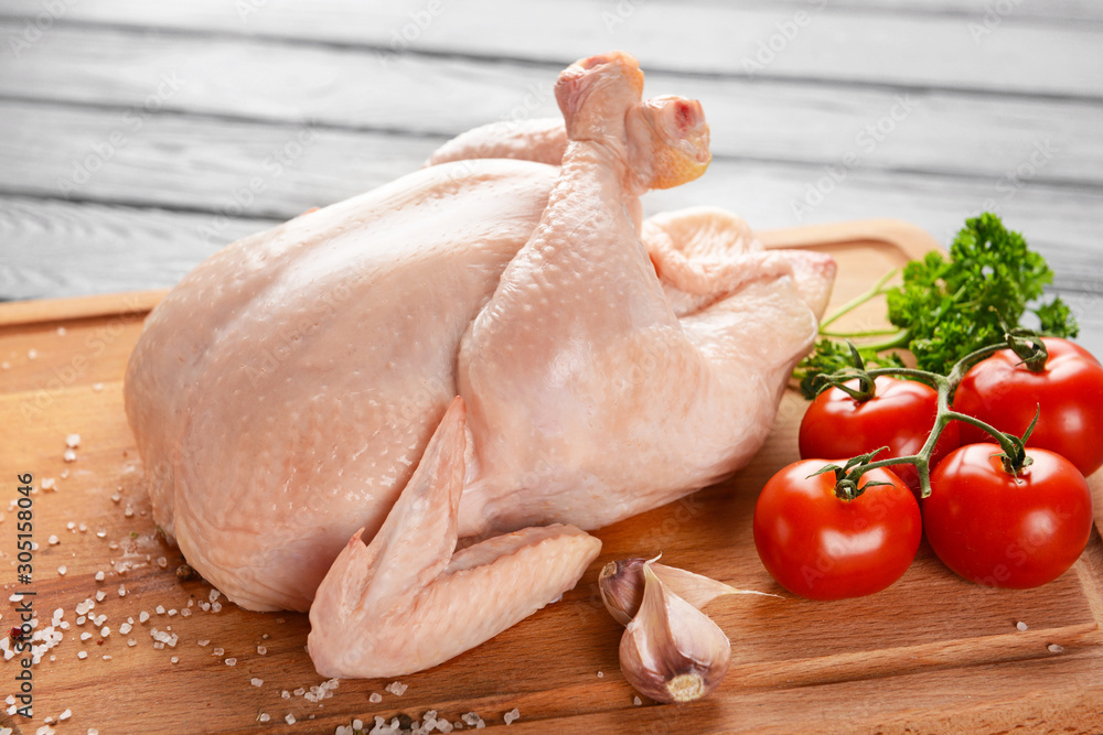 Raw chicken with spices and tomato on wooden background