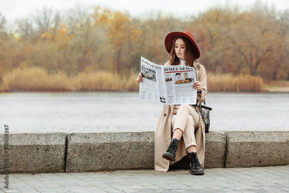 时尚年轻女人的画像，户外拿着报纸