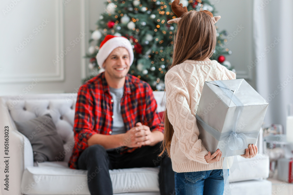 Little girl giving Christmas present to her father at home