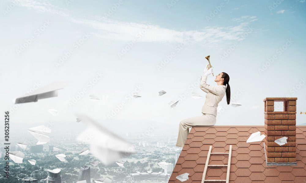 Beautiful young woman playing trumpet on roof