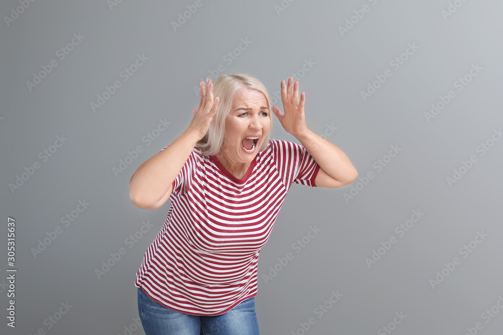 Angry mature woman on grey background