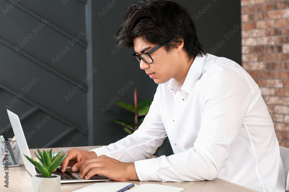 Asian programmer working on laptop in office