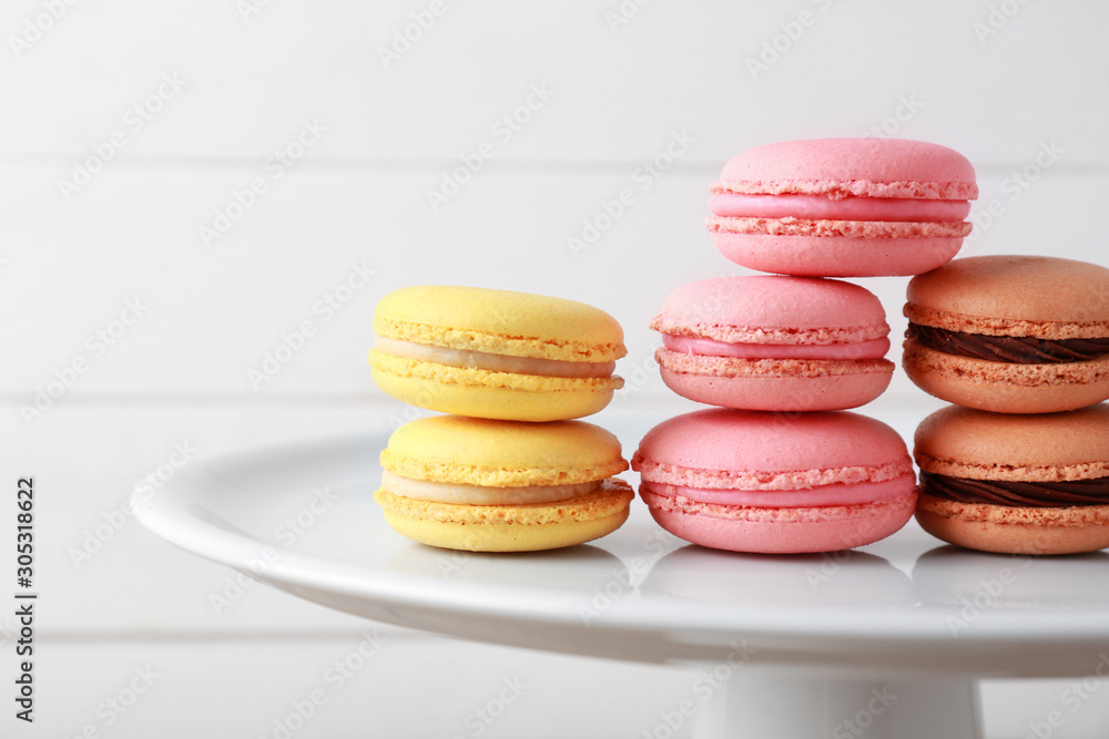 Stand with different tasty macarons on white background, closeup