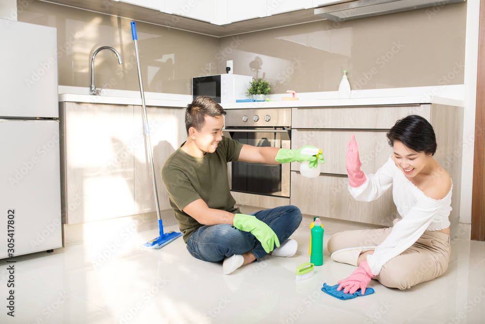 Modern kitchen - smiling young Asian woman and man cleaning the floor at home