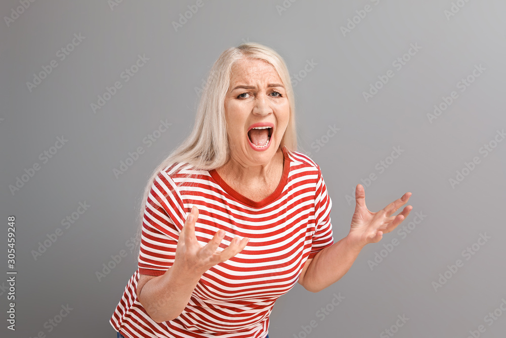 Angry mature woman on grey background