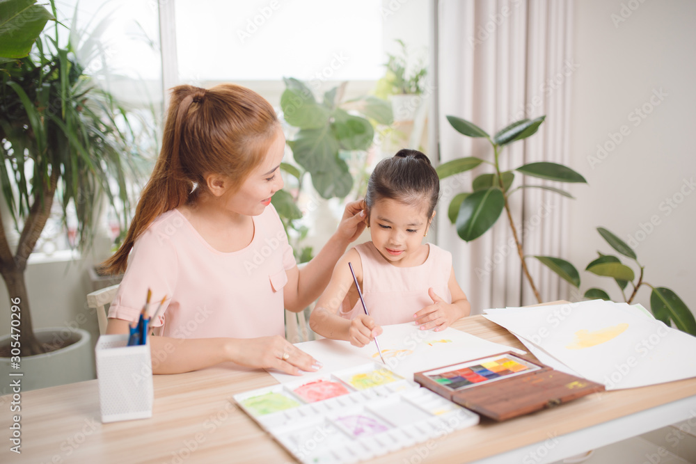 Little girl painting with her mother laying in livingroom