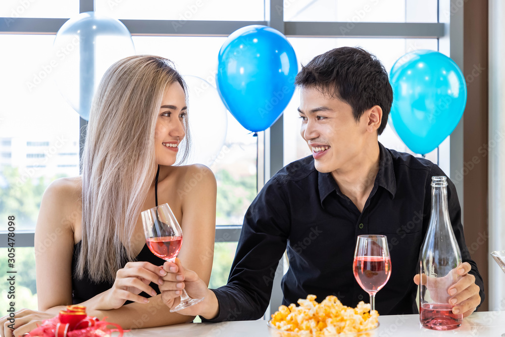 迷人的年轻男女在办公室派对上庆祝圣诞节和新年，男人送一杯