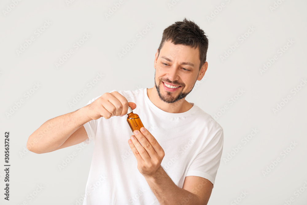 Handsome man with cosmetic product on white background