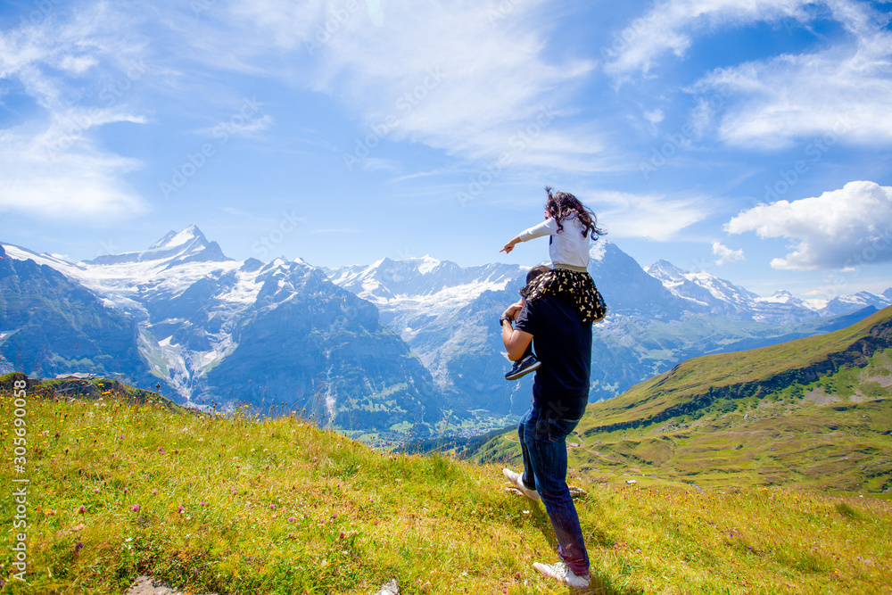 Picture of a father and daughters family is looking at view of the mountain Grindelwald First. It i