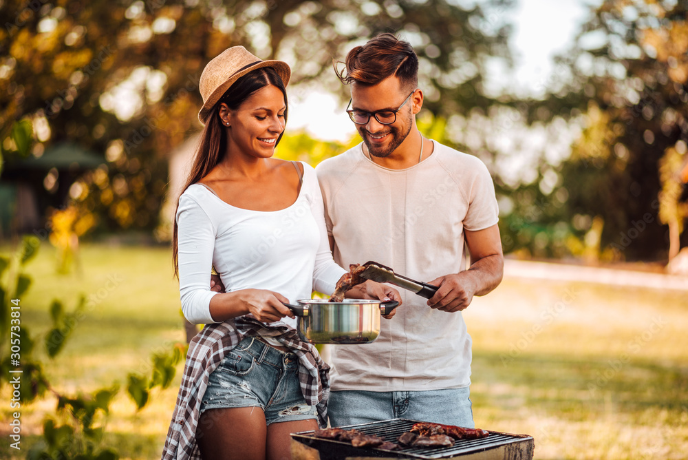 Young hipster couple on a vacation, making barbecue in nature.