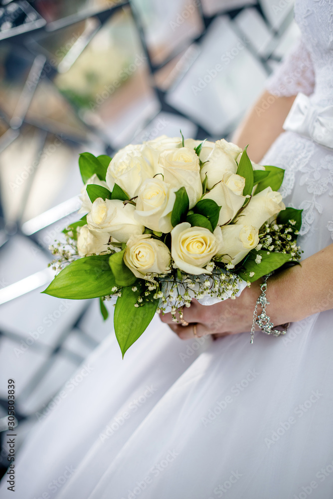 The bride is holding a bouquet of beige roses