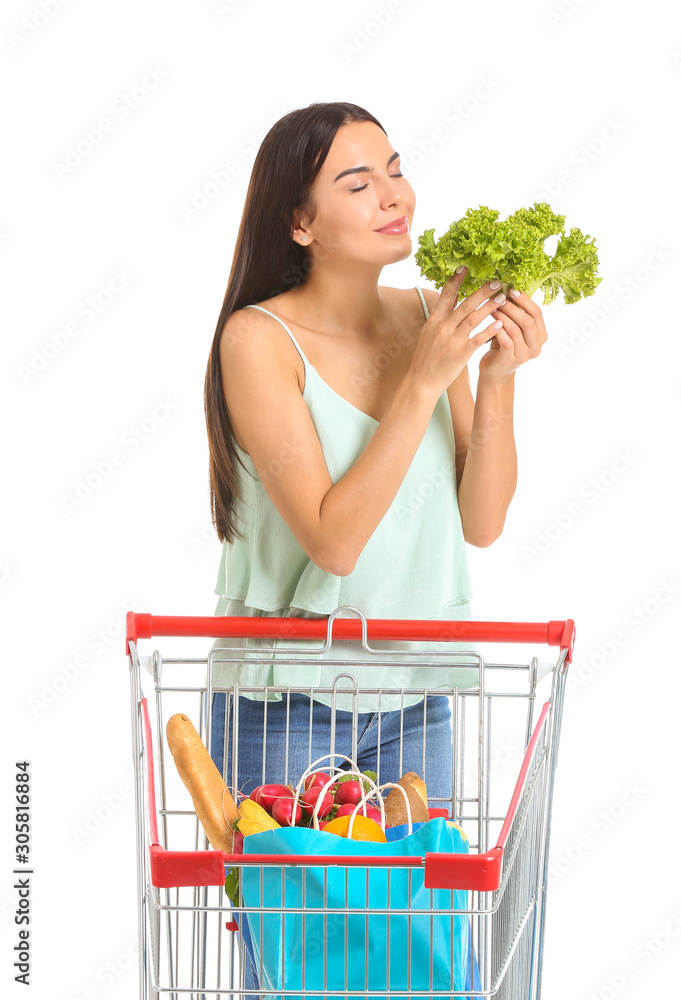 Young woman with shopping cart on white background