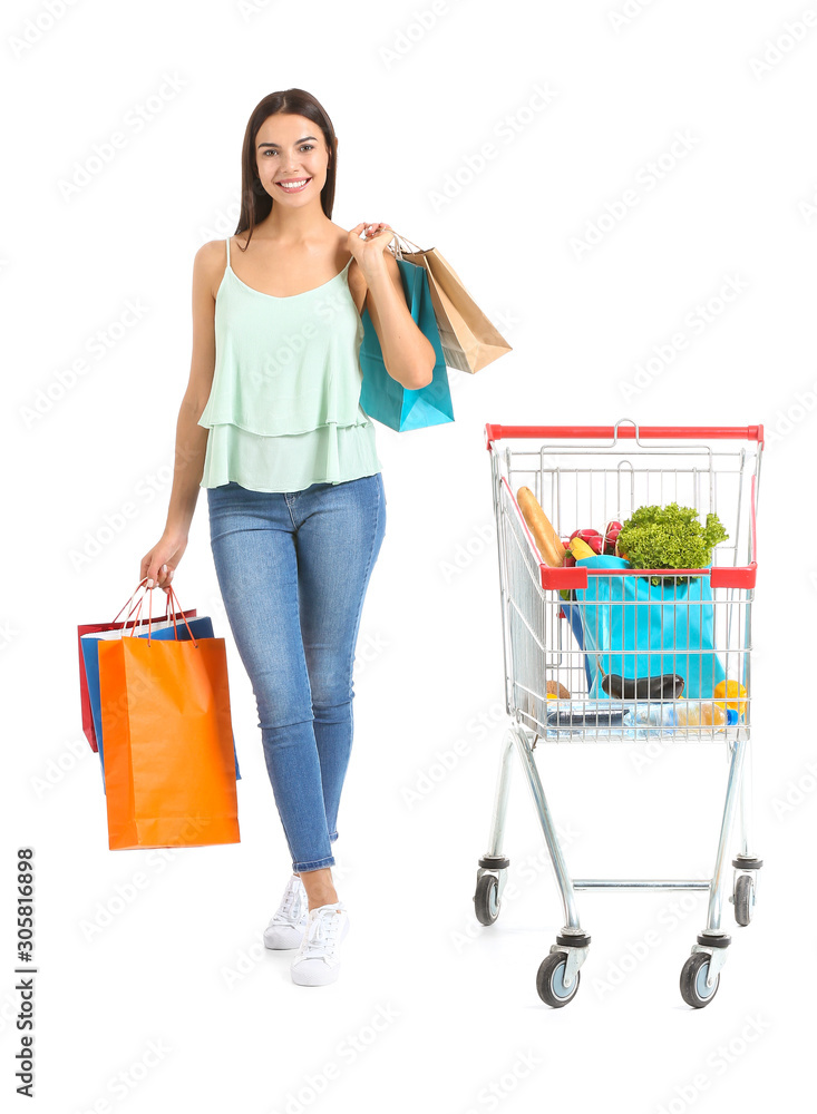 Young woman with shopping cart and bags on white background