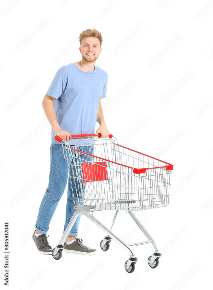 Young man with empty shopping cart on white background