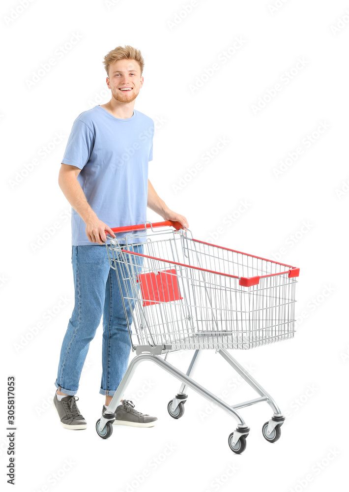 Young man with empty shopping cart on white background