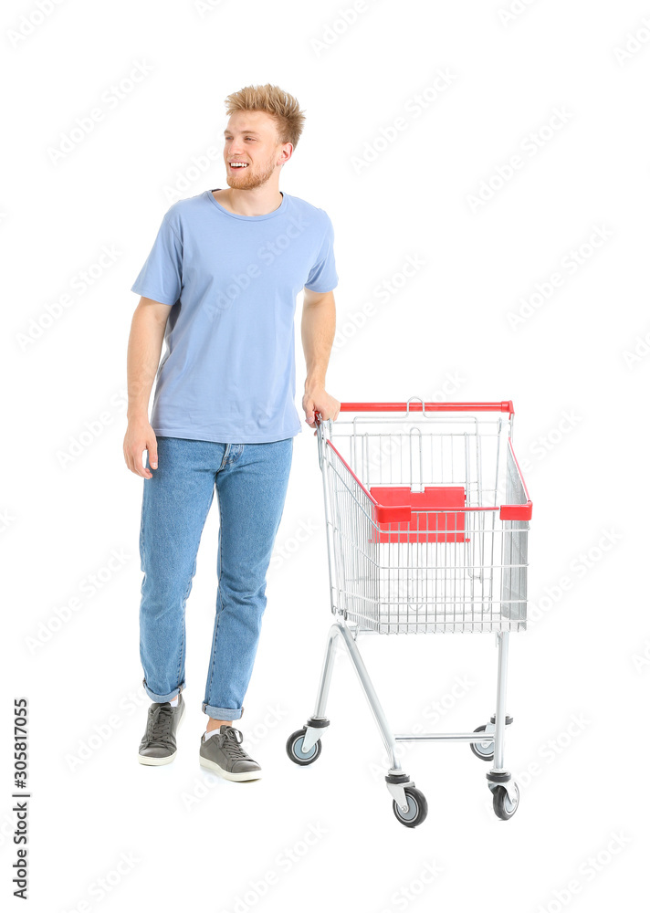 Young man with empty shopping cart on white background