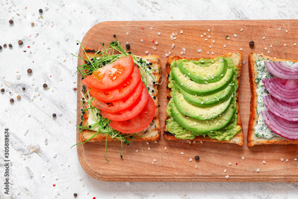 Wooden board with different tasty sandwiches on white background