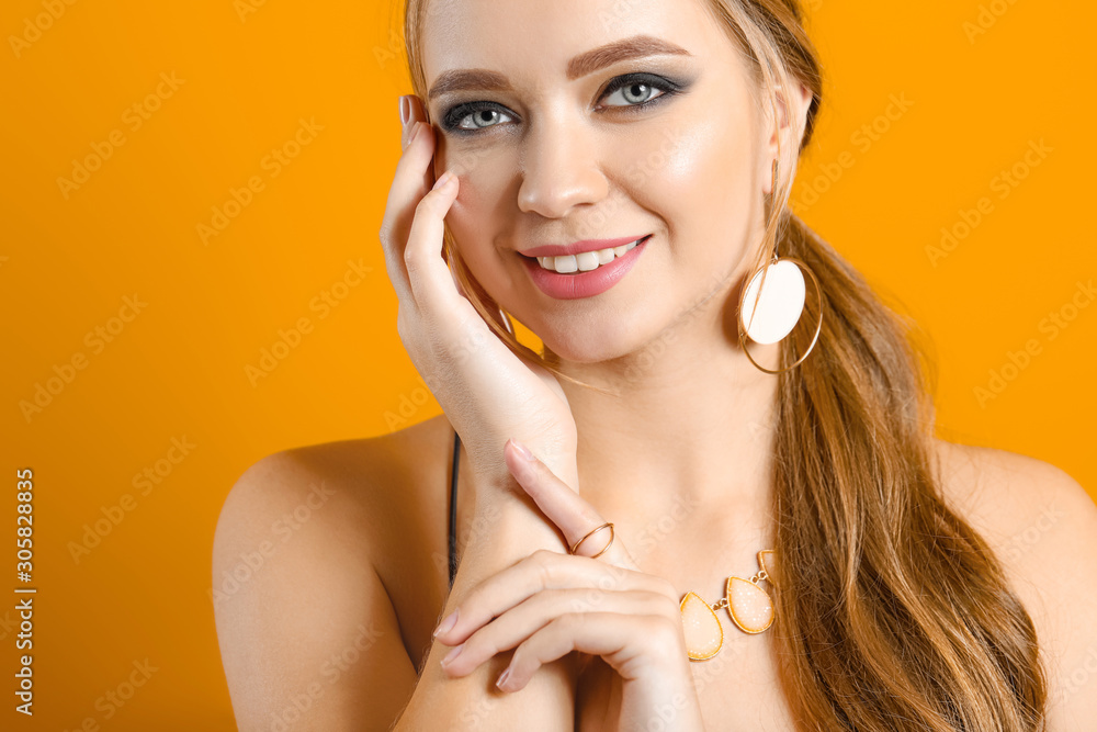 Young woman with beautiful jewelry on color background