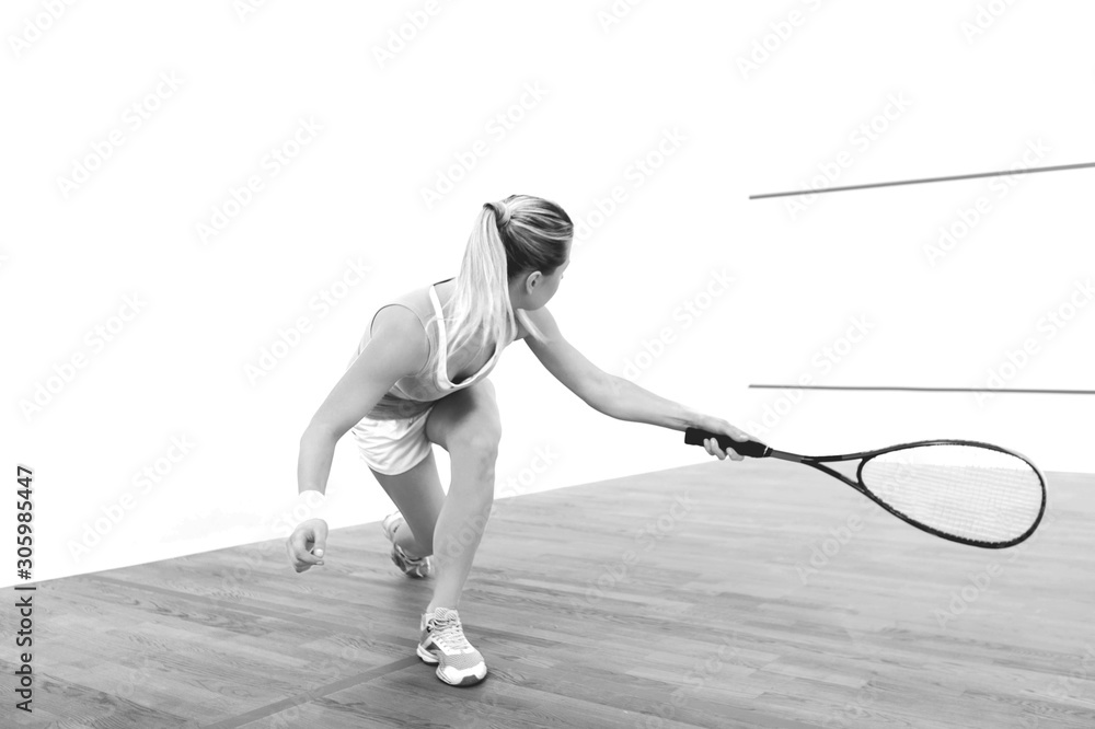 Attractive sports girl holding racket and playing squash on a court