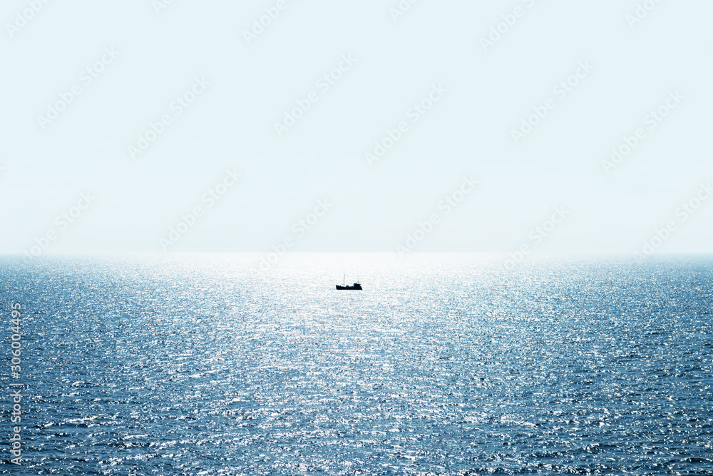 Lonely fishing ship trawler boat on ocean water. Calm clear sea sunny weather. Beautiful horizon of 