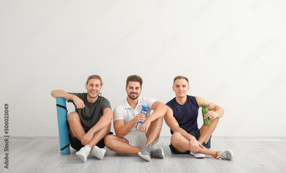 Group of sporty friends near white wall