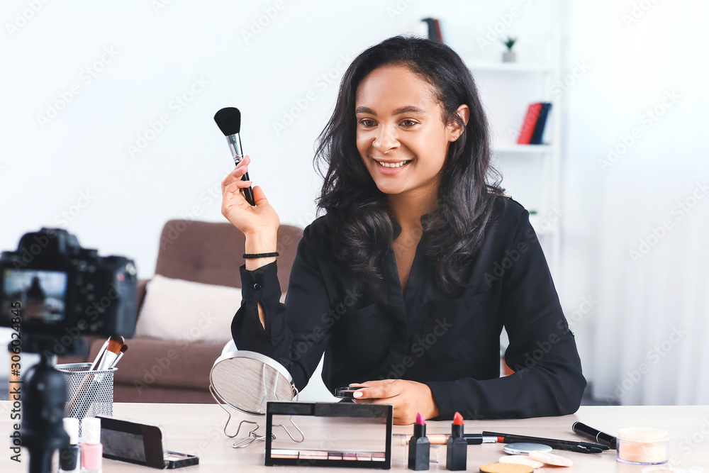 Young African-American beauty blogger recording video at home