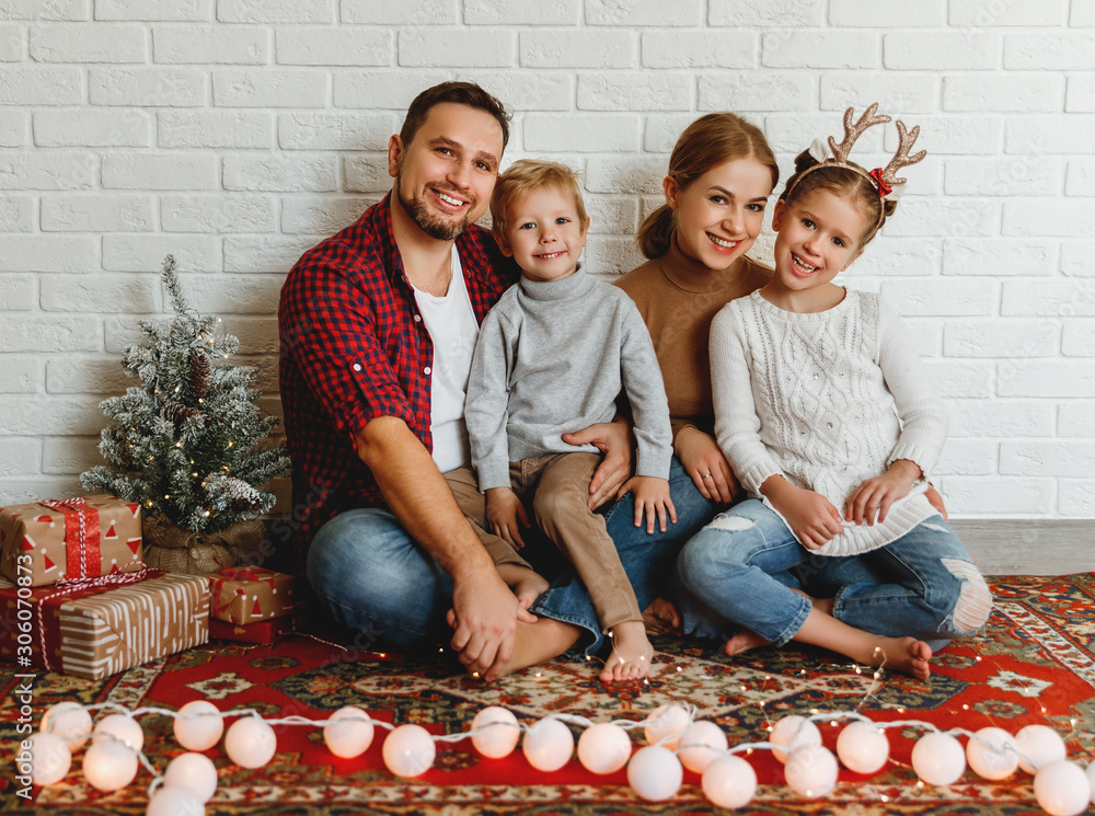 happy Christmas! family mother father and kids   before Christmas with garland   and tree.