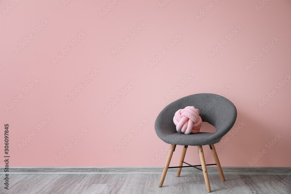 Stylish armchair with pillow near color wall