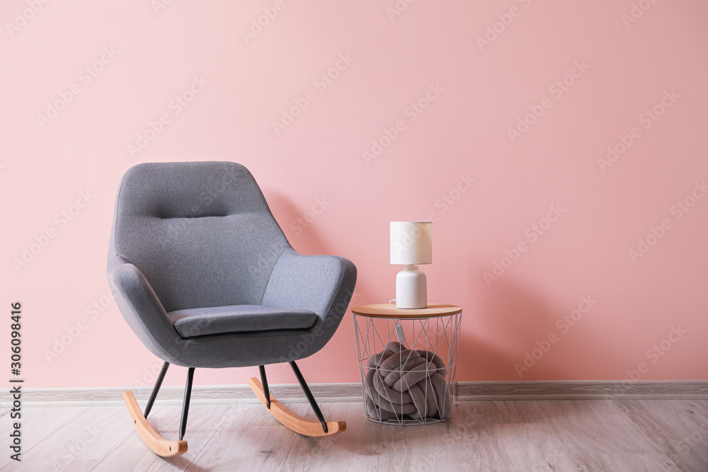 Soft rocking chair with table and lamp near color wall