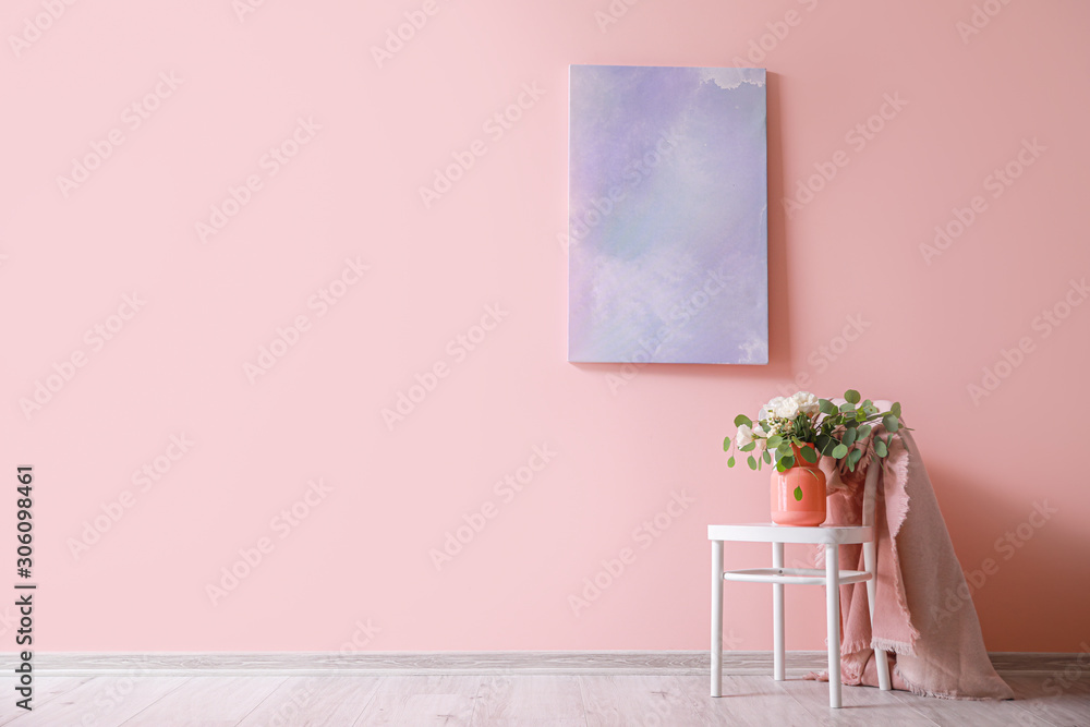 Chair with bouquet in vase and plaid near color wall