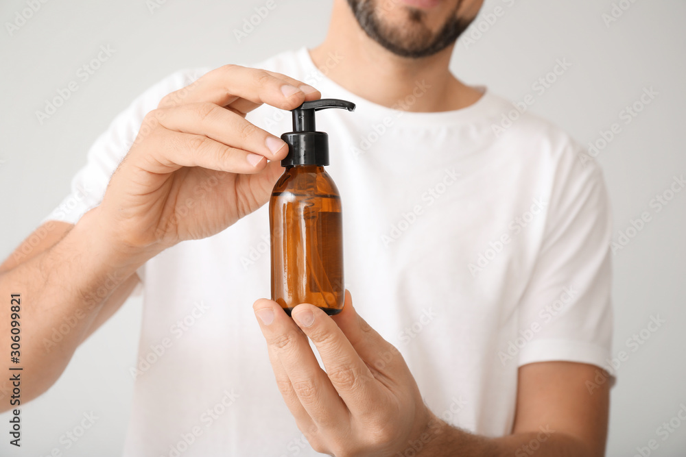 Handsome man with cosmetic product on white background, closeup