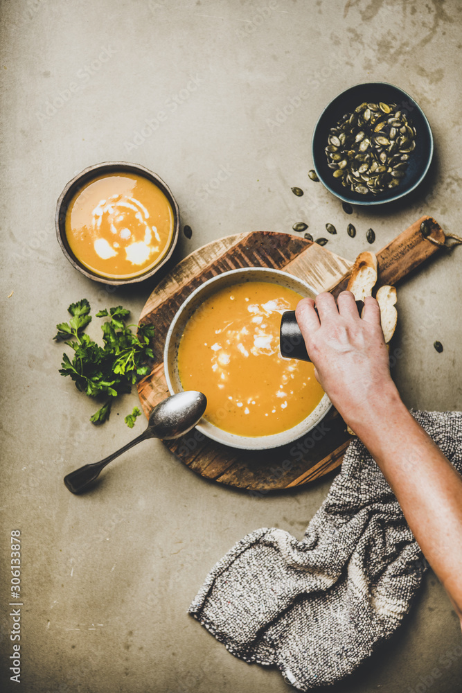 Autumn, winter warming seasonal dinner. Flat-lay of pumpkin soup with seeds, parsley, cream and brea