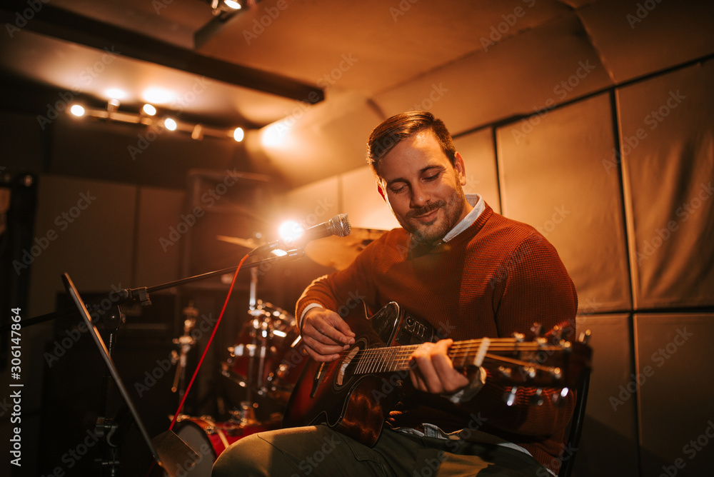 Portrait of a cheerful guitarist playing guitar.