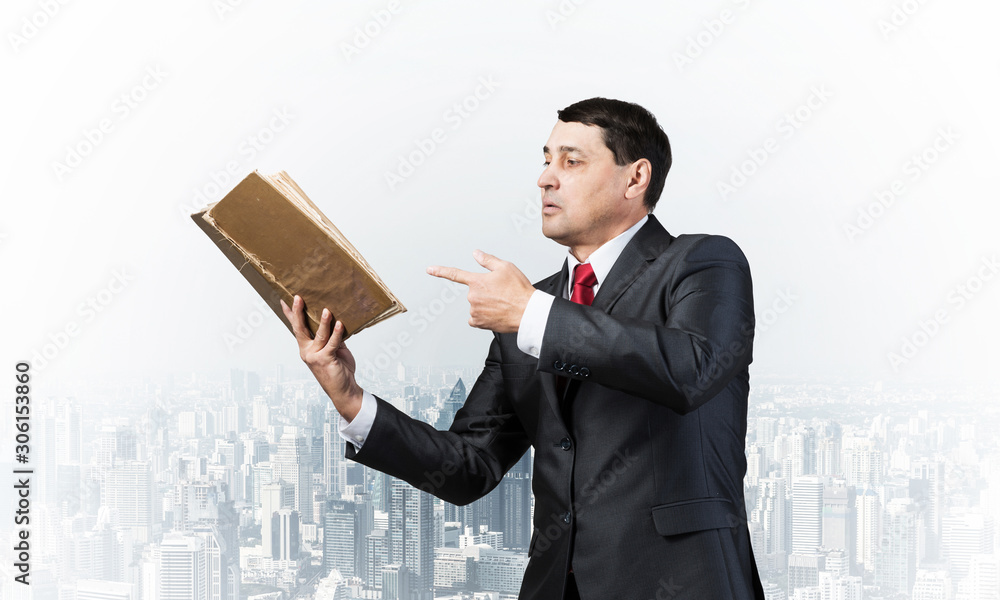 Senior businessman finger pointing into open book