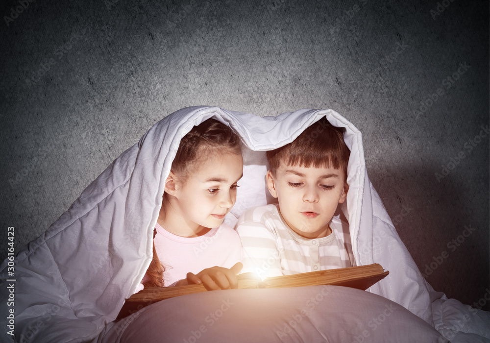 Engrossed little girl and boy reading book