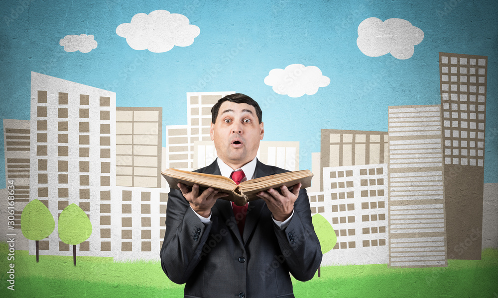 Surprised businessman holding open old book