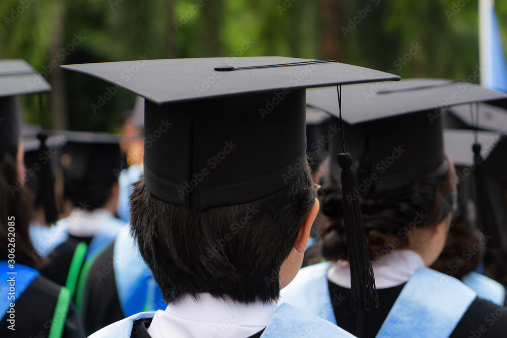 一群穿着黑色礼服的大学毕业生在大学毕业典礼上排队攻读学位的背影