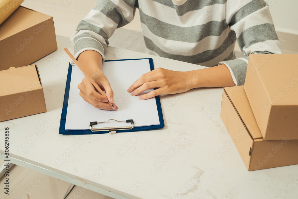 Close up of woman hand seller writing and checking product order.