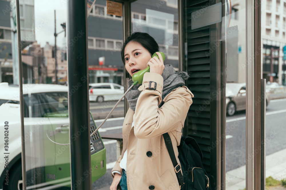 Young woman traveler calling with city call box in osaka japan. beautiful lady tourist with backpack