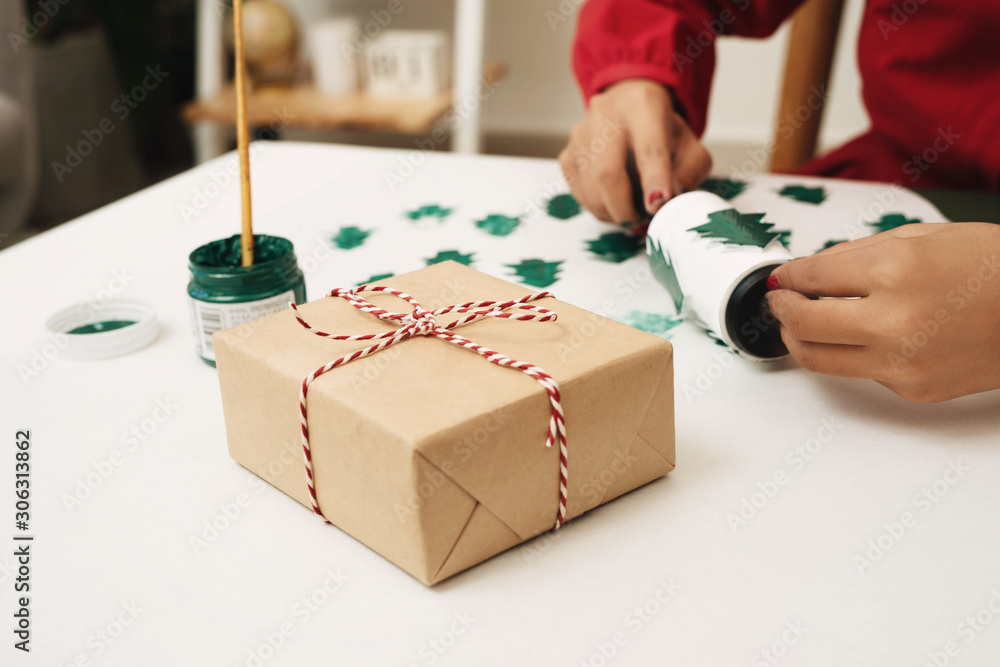 Close up of female hands making gift paper cover for Xmas. Noel concept.