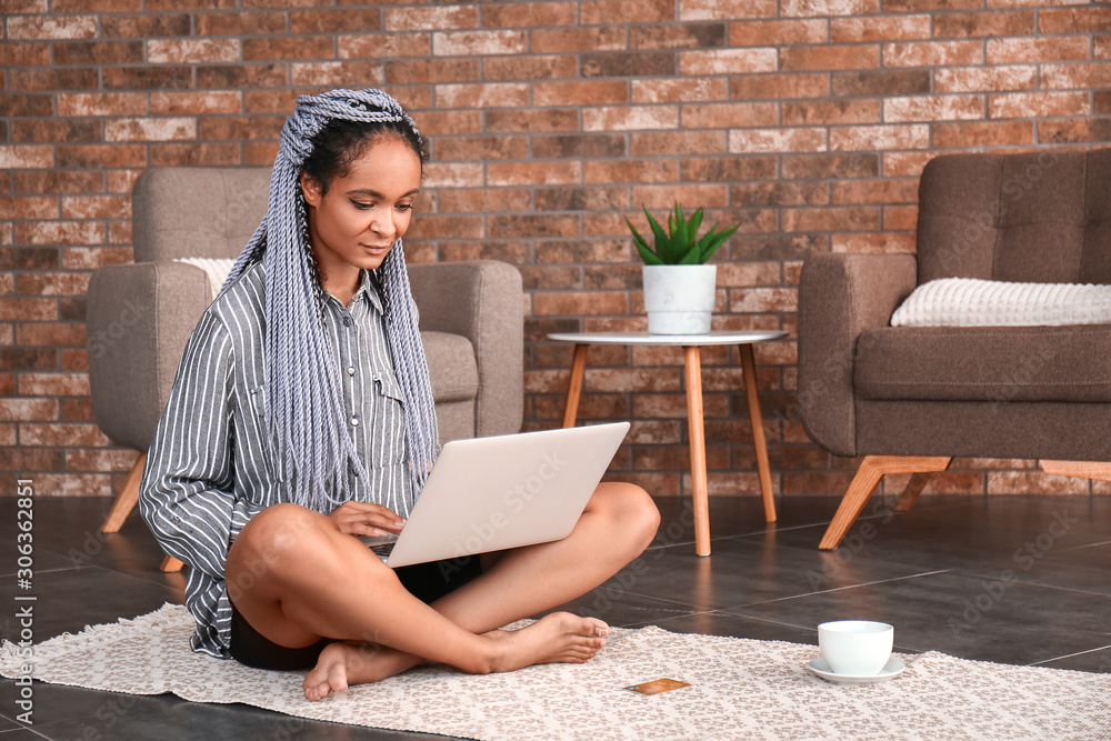 African-American woman using laptop for online shopping at home