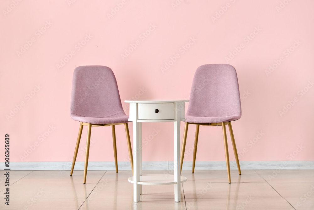 Table with chairs near color wall in room