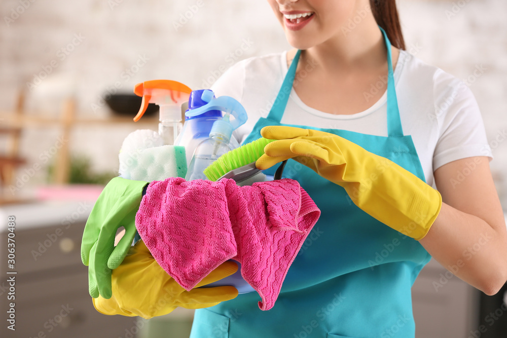 Female janitor with cleaning supplies in kitchen, closeup