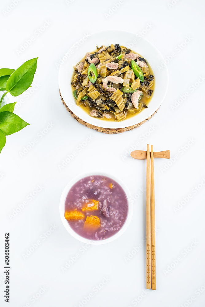 A dish of sauerkraut fried lean meat and a bowl of sweet potato porridge on white background